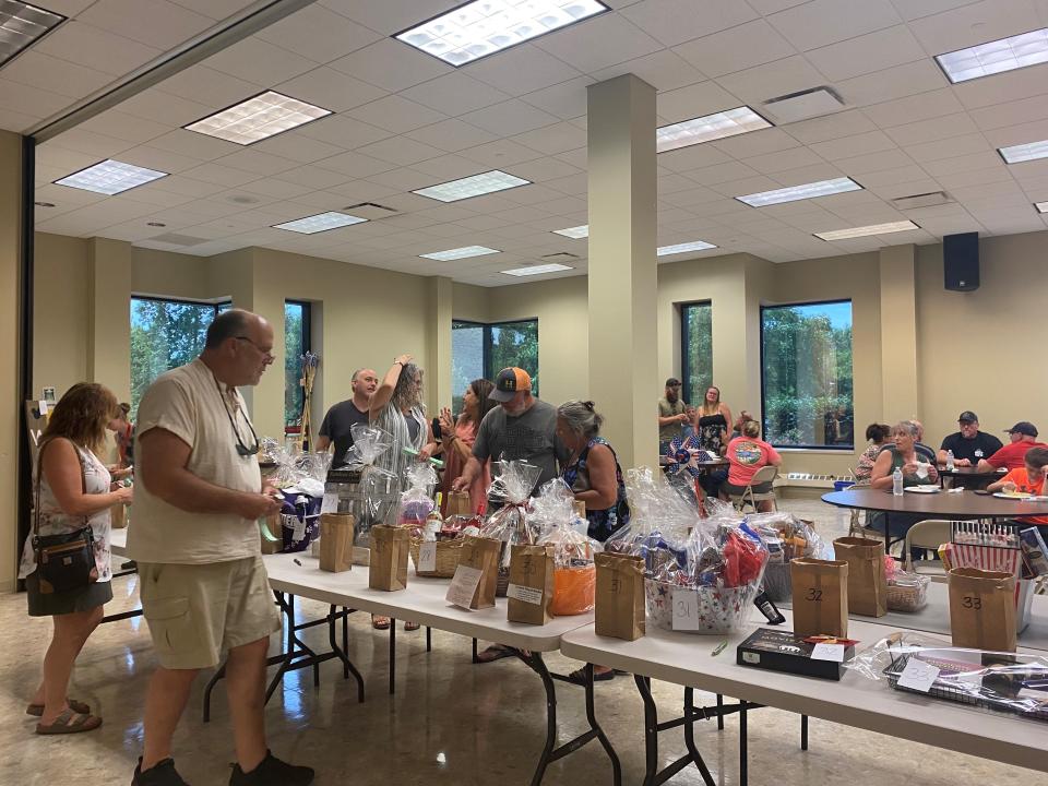 Attendees look at raffle baskets during the benefit dinner for Larry Nichols at Robertson Heating Supply on Saturday, June 25, 2022.