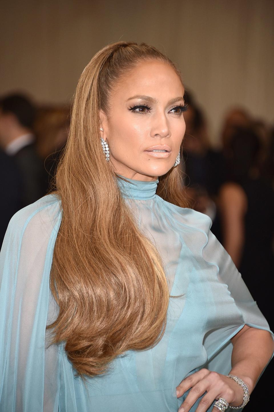 Jennifer Lopez in a turtleneck gown with sheer sleeves, long hairstyle, and sparkling jewelry
