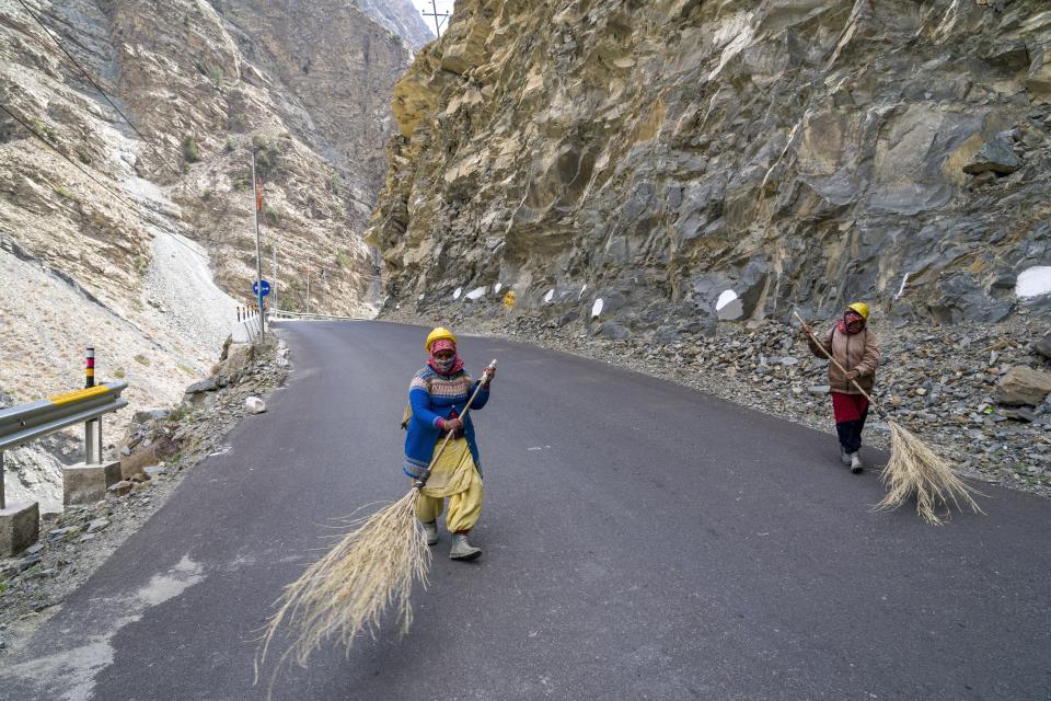 Women workers sweep the road to keep it clean of rock debris in Kinnaur district of the Himalayan state of Himachal Pradesh, India, Tuesday, March 14, 2023. (AP Photo/Ashwini Bhatia)