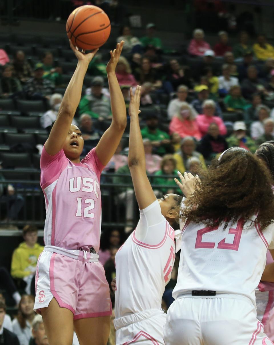 USC’s JuJu Watkins, left, shoots over the Oregon defense during the first half at Matthew Knight Arena in Eugene Friday, Feb. 16, 2024.