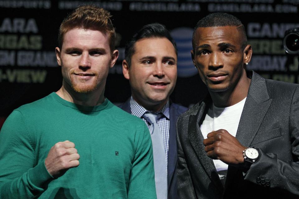 El púgil Saúl Canelo Álvarez, izquierda, y Erislandy Lara posan durante la conferencia de prensa previa a su pelea en el MGM Grand en Las Vegas, el jueves 10 de julio de 2014. En medio de ambos está Oscar De La Hoya, fundador de Golden Boy Promotions. (Foto AP/Las Vegas Review-Journal, Jason Bean)