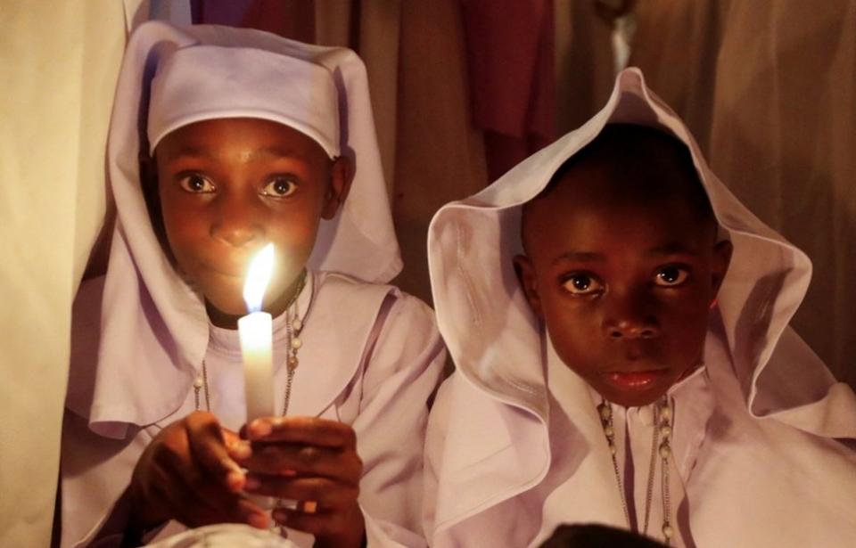 A child holds a candle during Easter vigil mass...