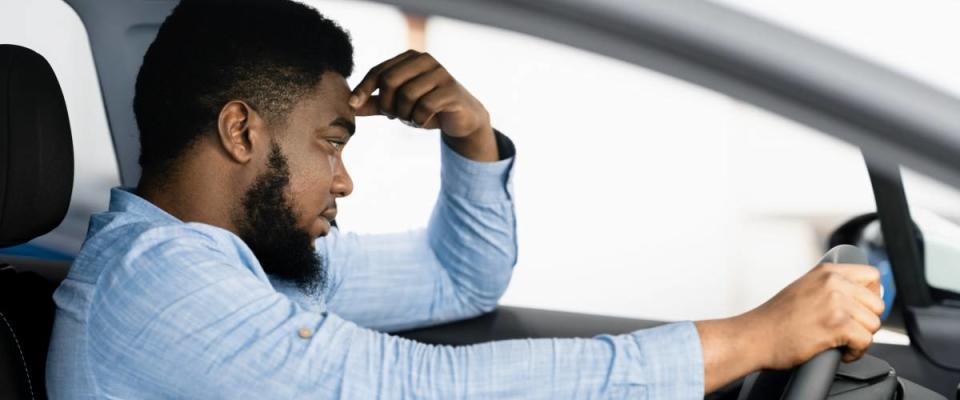 Man in car pinches his forehead