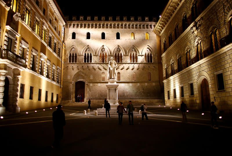 FILE PHOTO: People stroll in front of Monte dei Paschi bank headquarters downtown Siena