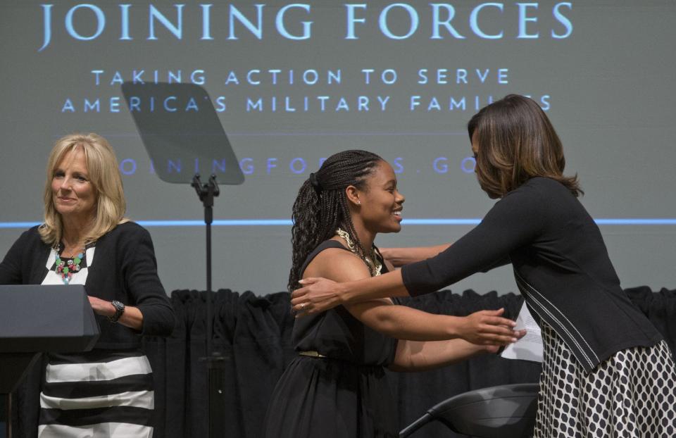 First lady Michelle Obama, right, hugs Chrissandra Jackson, center, accompanied by Dr. Jill Biden, left, at the third anniversary of Joining Forces, Wednesday, April 30, 2014, at the American Red Cross Hall of Service in Washington. Mrs. Obama announced pledges in excess of $150 million from foundations and corporations to help veterans and their families get the services they need in the places where they live as the country adjusts to a postwar footing. Jackson is a daughter of a military family. (AP Photo)