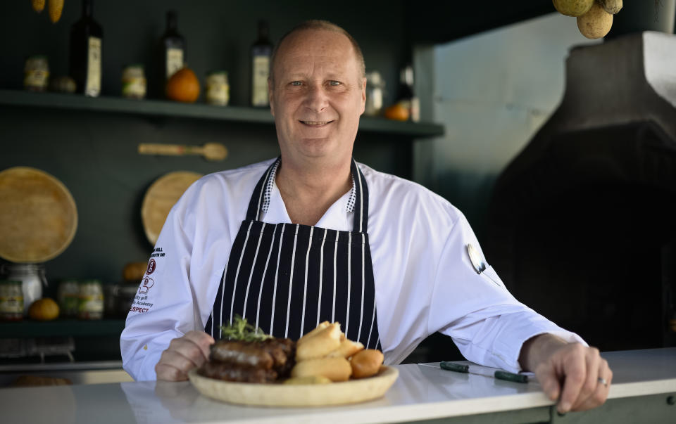 Kevin Hill, Executive Chef at a popular Romanian restaurant poses next to a plate of 'mici', the Romanian version of a Turkish dish, spicy grilled sausages, popular across the Balkans, in a restaurant in Bucharest, Romania, Sunday, Feb. 16, 2014. Officials in Brussels have agreed that spicy “mici", grilled meat bullet shaped delicacies which rely on a pinch of bicarbonate of soda for their distinctive succulent flavor and puffy texture will be permitted under European Union rules, the Romanian Meat Association says.(AP Photo/Octav Ganea/Mediafax) ROMANIA OUT