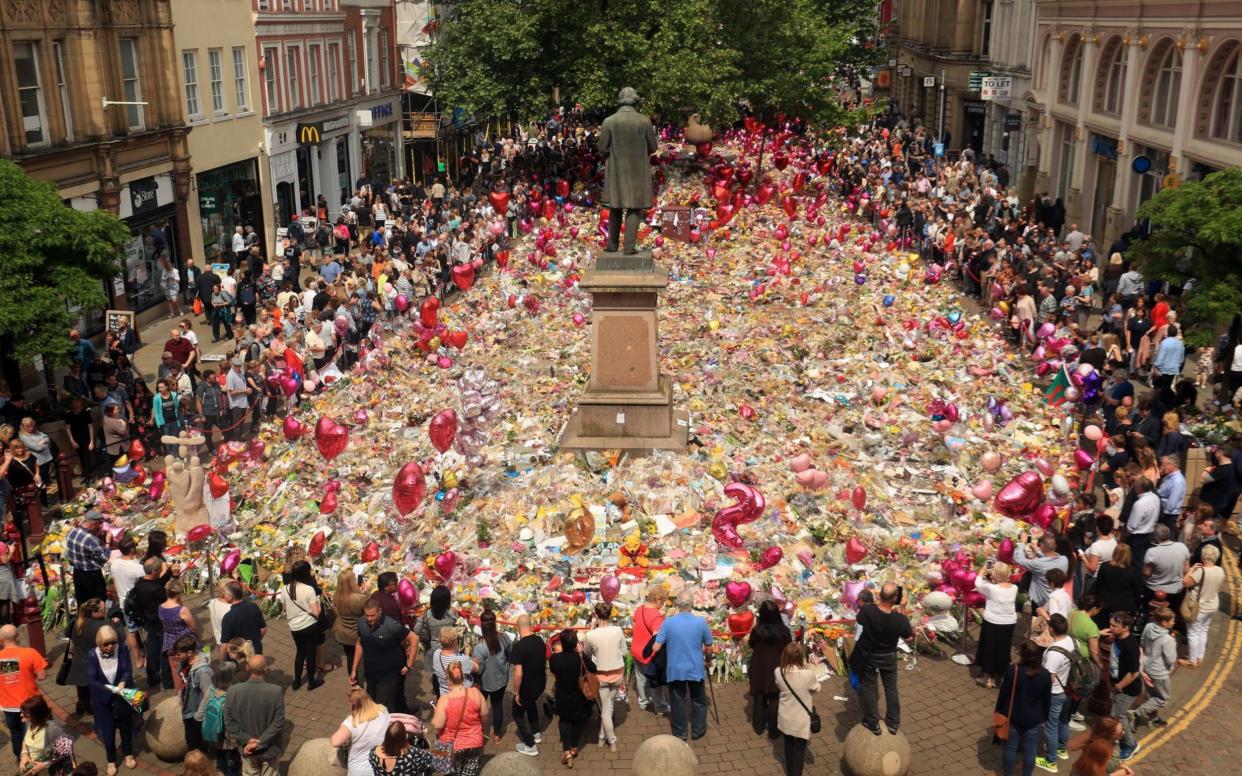 People look at flowers and tributes left in St Ann's Square in Manchester following the Manchester Arena terror attack - PA