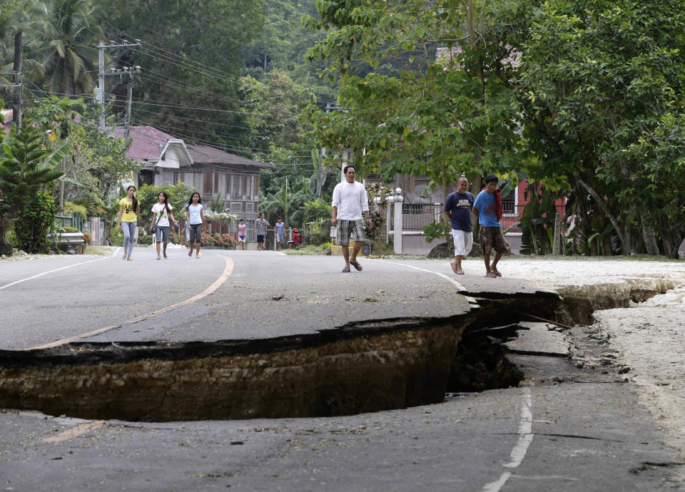 Residents walk on a damaged highway in Loboc township, Bohol province in central Philippines Wednesday Oct. 16, 2013, a day after a 7.2-magnitude quake hit Bohol and Cebu provinces. The tremor collapsed buildings, cracked roads and toppled the bell tower of the Philippines' oldest church Tuesday morning, causing multiple deaths across the central region. (Bullit Marquez/AP)
