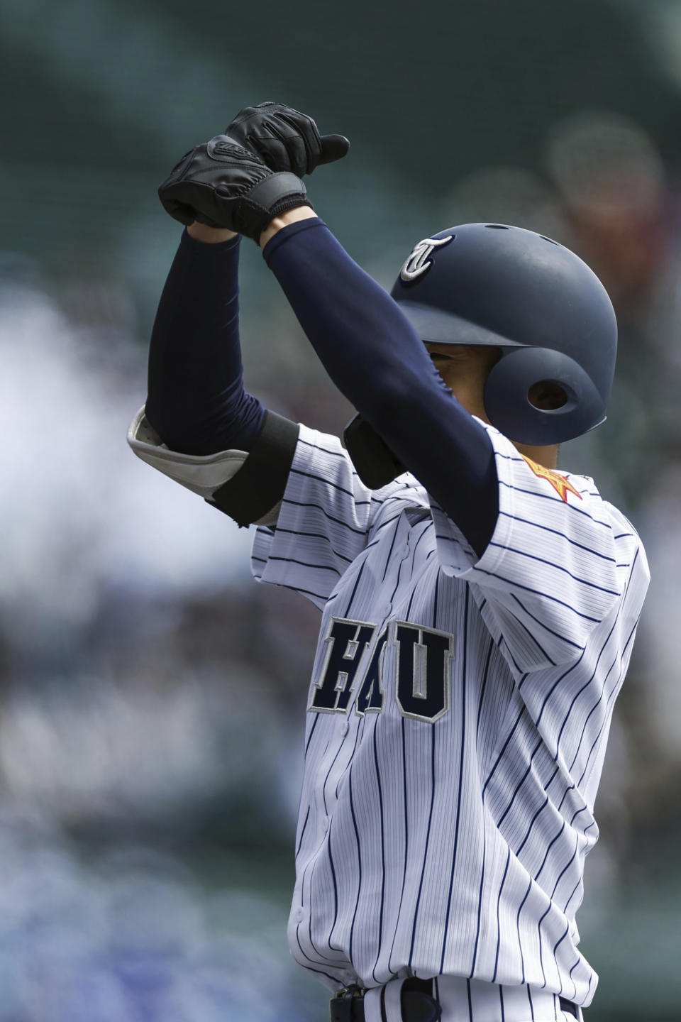 A player for Tohoku High School gestures after getting on first base during their game against Yamanashi Gakuin Senior High School at a stadium in Nishinomiya, Osaka, western Japan Saturday, March 18, 2023. Lars Nootbaar's imaginary pepper-grinder was the talk of World Baseball Classic games in Japan, but the fun-loving gesture by the St. Louis Cardinals outfielder does not appear welcome in Japan's popular high school baseball tournament.(Kyodo News via AP)