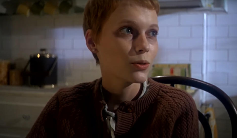 Mia Farrow as Rosemary Woodhouse is sitting down and looking across the kitchen.