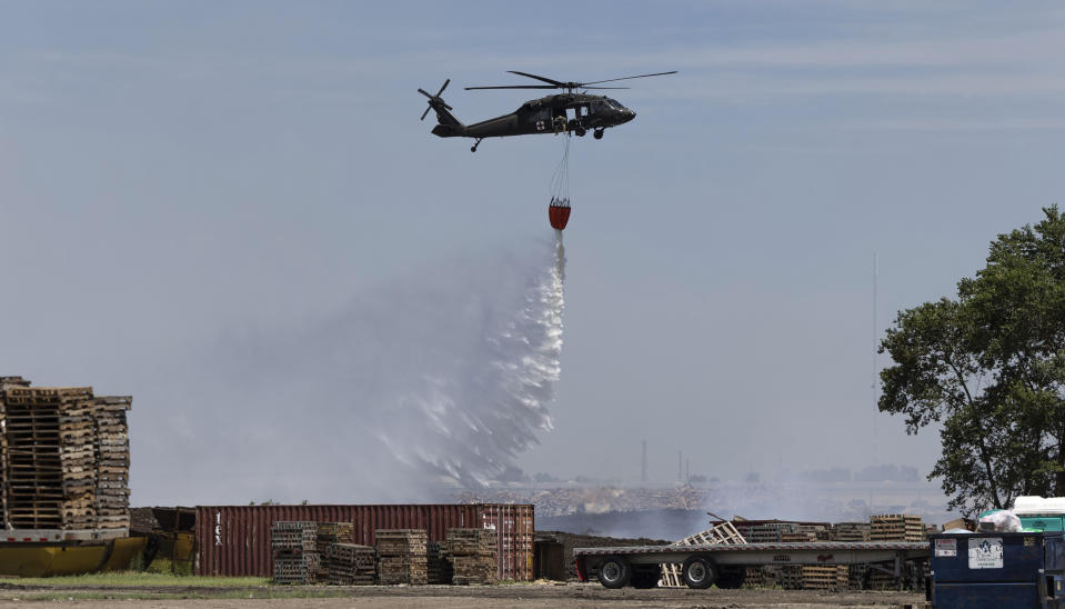 A helicopter from the Kansas Air National Guard drops water over a fire at Evergreen Recycle in Park City, Kan. on Tuesday, June 25, 2024. The fire broke out Sunday evening and has continued to burn since. Sedgwick County Fire Marshal Brad Crisp said during a Tuesday morning press conference that no cause for the fire has been determined. (Travis Heying/The Wichita Eagle via AP)