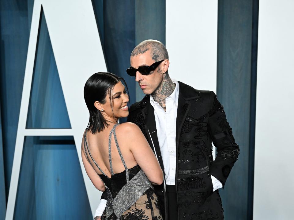 Kourtney in a beige, black, and silver gown with lace, cutouts, and straps.