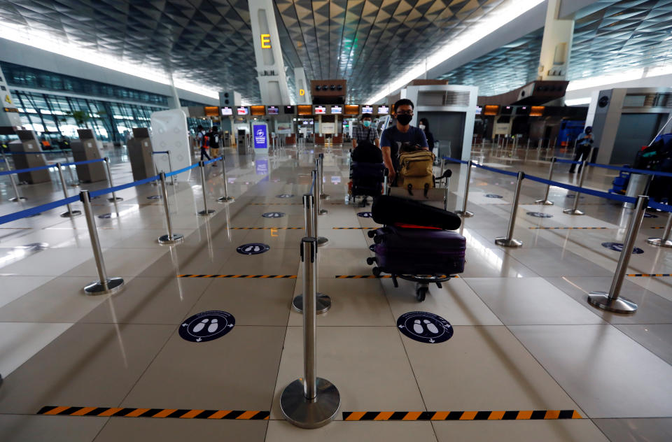 En las colas antes de acceder al avión, los pasajeros guardan la distancia de seguridad. En muchos aeropuertos, como el de Soekarno-Hatta de Tangerang (Indonesia), han colocado marcas en el suelo. (Foto: Willy Kurniawan / Reuters).