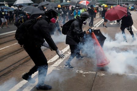Masked protesters react in a cloud of tear gas during an anti-government rally in central Hong Kong