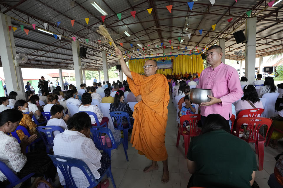 A Buddhist monk splashes holy water to the relatives of the victims during the Buddhist ceremony in the rural town of Uthai Sawan, in Nong Bua Lamphu province, northeastern Thailand, Friday, Oct. 6, 2023. A memorial service takes place to remember those who were killed in a grisly gun and knife attack at a childcare center. A former police officer killed 36 children and teachers in the deadliest rampage in Thailand's history one year ago. (AP Photo/Sakchai Lalit)