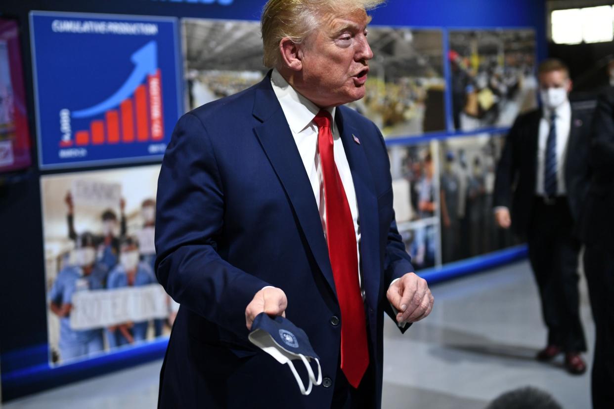 Donald Trump holds a face mask emblazoned with the presidential seal on a visit to a Ford manufacturing plant in Michigan: AFP via Getty Images