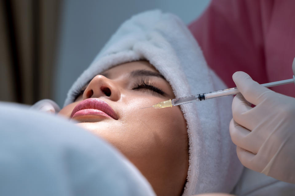 A young woman receives an injectable cosmetic treatment in her cheer