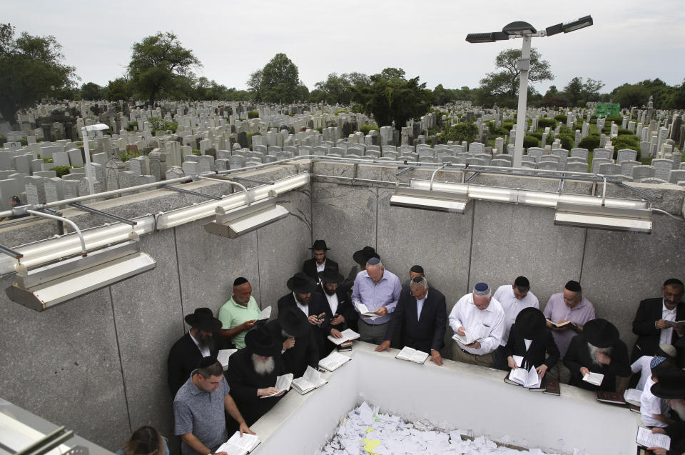 In this July 2, 2019 photo, people pray at the gravesite of Rabbi Menachem M. Schneerson in the Queens borough of New York. While visitors come year-round, the crowds grow tremendously around the anniversary of his passing, which according to the Hebrew calendar falls this year on July 6, with people sometimes waiting a few hours to spend even a couple of moments at his mausoleum, where they pray and leave notes. (AP Photo/Seth Wenig)