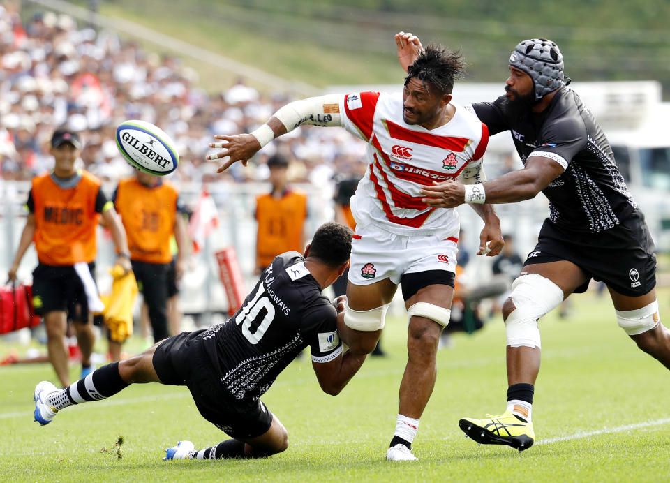 Amanaki Lelei Mafi, center, is tackled by Fiji's Ben Volavola, left, during a Pacific Nations Cup rugby match at Kamaishi Recovery Memorial Stadium in Kamaishi, northern Japan, Saturday, July 27, 2019. Japan took big step forward in Rugby World Cup preparation with a five-try 34-21 win over Fiji in Pacific Nations Cup (Meika Fujio/Kyodo News via AP)