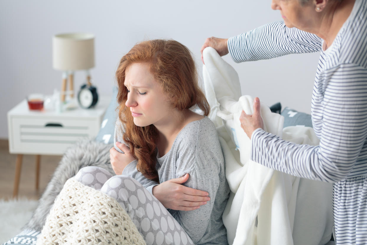 Mother taking care about sick daughter while sitting on bed with fever and headache