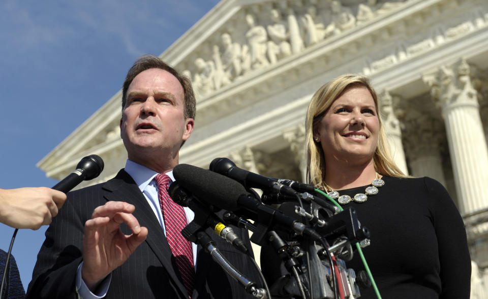 FILE - Michigan Attorney General Bill Schuette, left, standing with Jennifer Gratz, Chief Executive Officer of XIV Foundation, speaks to reporters after arguing their case before the Supreme Court in Washington, Oct. 15, 2013. Gratz, a white woman who was denied undergraduate admission to the University of Michigan won her case. The Supreme Court agreed that the school's undergraduate admissions system was flawed because it relied too heavily on race. (AP Photo/Susan Walsh, File)