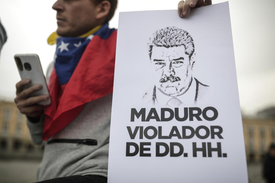 A woman holds a sign with an image depicting Venezuelan President Nicolas Maduro and a message that reads in Spanish: "Maduro, human rights violator ", during a protest in Plaza de Bolivar, as international delegates gather for a conference focused on Venezuela’s political crisis, at the San Carlos Palace, also known as the Foreign Ministry, in Bogota, Colombia, Tuesday, April 25, 2023. (AP Photo/Ivan Valencia)