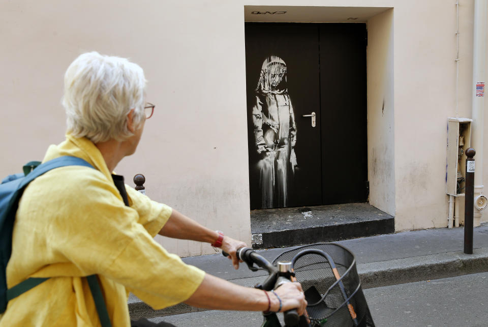 PARIS, FRANCE - JUNE 26:  A woman views a recent artwork attributed to street artist Banksy on June 26, 2018 in Paris, France.  Yesterday a new artwork attributed to street artist Banksy was discovered on a side street to the Bataclan concert hall where a terrorist attack killed 90 people on November 13, 2015. Between 22 and 24 June, six new works were discovered in Paris and can, by their style, belived to be creations of Banksy. On one of them, one can see a virulent denunciation of the government's policy on migrants. Urban artist Banksy is known around the world for stenciling on city walls. This would be the first incursion of the artist into Parisian street art.  (Photo by Chesnot/Getty Images)