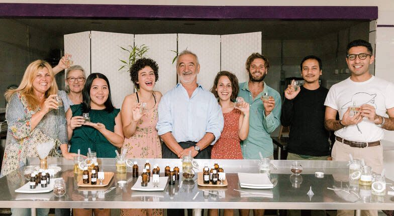 A group of people smiling holding their small glass bottles of perfume. 