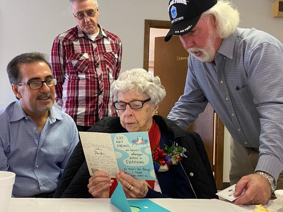 WWII veteran Judith Barstow, center, reads a final message from her late sister, Elizabeth, at Judith's 100th birthday party on Feb. 25, 2024, with her nephews John Burns, left, and Mark Burns, right, and her step-son Ed Barstow, back at Pine Hill Estates in Raynham.