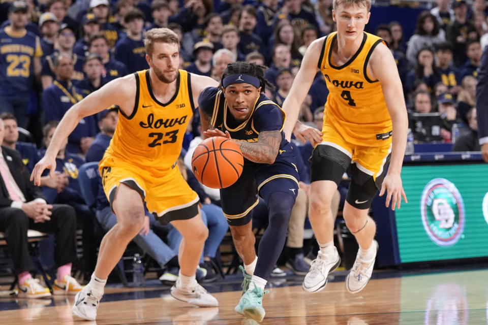 Michigan guard Dug McDaniel (0) drives between Iowa forward Ben Krikke (23) and guard Josh Dix (4) during the second half of an NCAA college basketball game, Saturday, Jan. 27, 2024, in Ann Arbor, Mich. (AP Photo/Carlos Osorio)