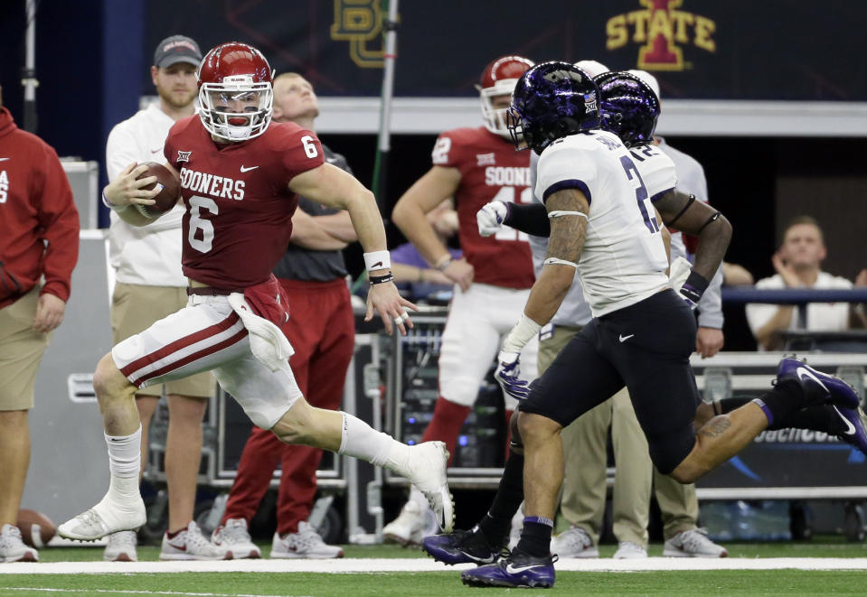 Baker Mayfield (L) gains yardage as he runs the ball as TCU safety Niko Small (R) gives chase on Saturday, Dec. 2, 2017, in Arlington, Texas. (AP Photo/Tony Gutierrez)