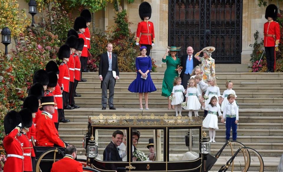 The royal wedding party gather on the steps to wave the bride and groom off for their carriage ride.