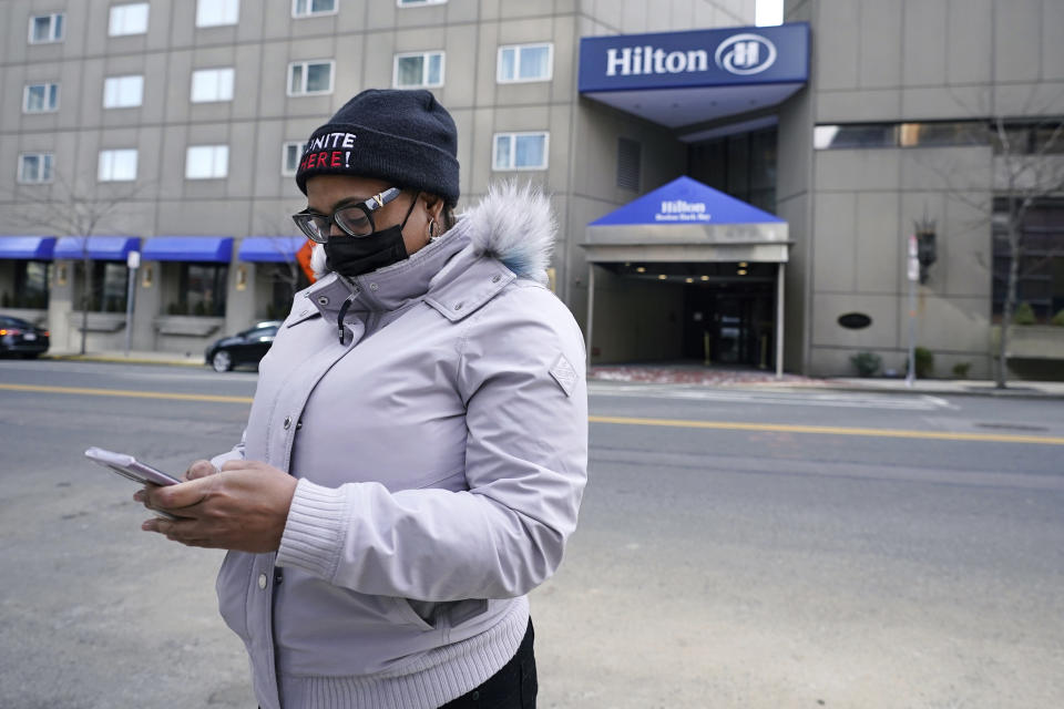 Hotel housekeeper Esther Montanez looks at her cell phone outside the Hilton Back Bay, Friday, March 5, 2021, in Boston. Montanez refuses to give up hope of returning to her cleaning job at the hotel, which she held for six years until being furloughed since March 2020 due to the COVID-19 virus outbreak. The single mother cannot bear the idea of searching for work that will almost certainly mean earning near the minimum wage. (AP Photo/Charles Krupa)