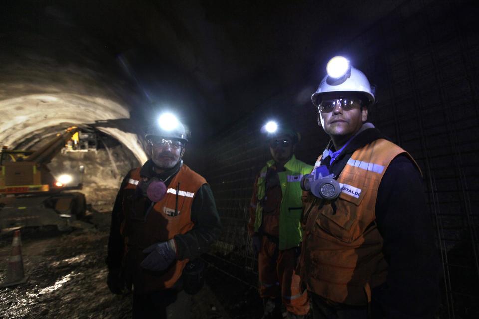 In this Sept. 25, 2012 photo, foreman Jorge Villanueva, left, and supervisor Omar Rosales, right, look toward the entrance of a tunnel drilled under the Chuquicamata copper mine in the Atacama desert in northern Chile. Experts say that by 2019 the Chuquicamata copper mine will be unprofitable, so state-owned mining company Codelco is trying to head off closure by converting the open pit into the world's largest underground mine. Codelco believes the mine still has much more to give, with reserves equal to about 60 percent of all the copper exploited in the mine's history still buried deep beneath the crater. (AP Photo/Jorge Saenz)