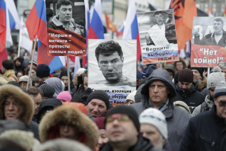 Demonstrators, with flags of different opposition movements and portraits of Boris Nemtsov, march in memory of opposition leader Boris Nemtsov in Moscow, Russia, Sunday, Feb. 24, 2019. Thousands of Russians took to the streets of downtown Moscow to mark four years since Nemtsov was gunned down outside the Kremlin. (AP Photo/Pavel Golovkin)