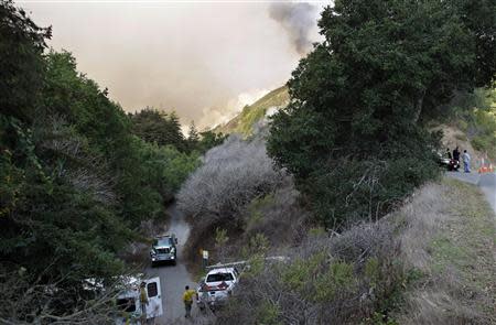 Police and fire vehicles sit at the entrance to a canyon during a wild fire in Big Sur, California, December 17, 2013. REUTERS/Michael Fiala