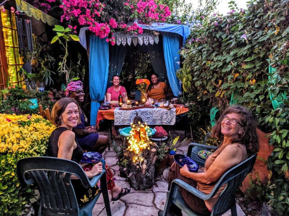 The author and her friends sitting outside in a garden with small lights, green plastic chairs, and blankets placed around the patio.