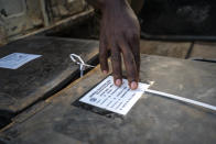 A police officer checks voting material at a polling station in Kampala, Uganda, Thursday, Jan. 14, 2021. Ugandans are voting in a presidential election tainted by widespread violence that some fear could escalate as security forces try to stop supporters of leading opposition challenger BobiWine from monitoring polling stations.(AP Photo/Jerome Delay)