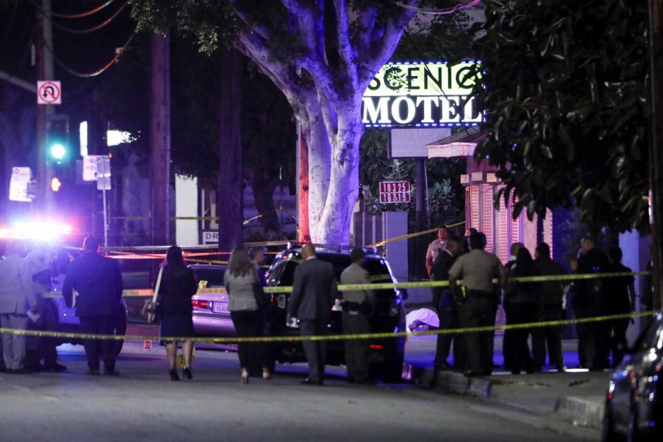 Police and other law enforcement at a cordoned-off crime scene in front of a motel