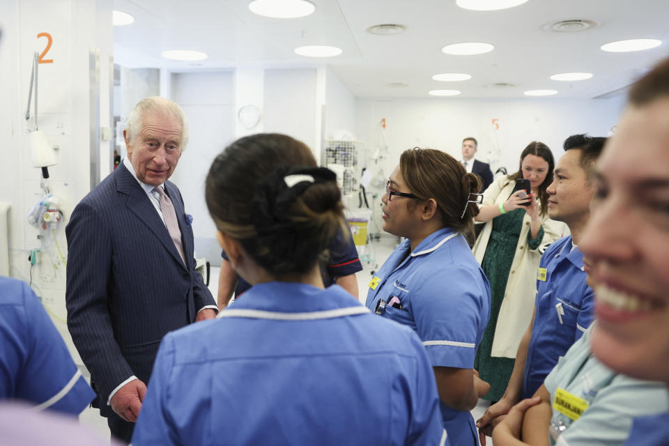 FILE - Britain's King Charles III meets with staff members during a visit to the University College Hospital Macmillan Cancer Centre in London, Britain, Tuesday,April 30, 2024. King Charles III’s decision to be open about his cancer diagnosis has helped the new monarch connect with the people of Britain and strengthened the monarchy in the year since his dazzling coronation at Westminster Abbey. (Suzanne Plunkett/Pool photo via AP, File)