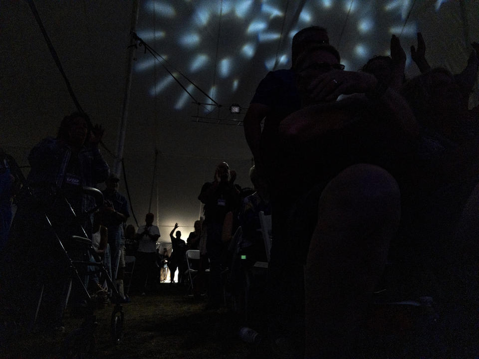 FILE - A person in the audience is silhouetted as they stand at the edge of the tent during the ReAwaken America Tour at Cornerstone Church in Batavia, N.Y., Aug. 12, 2022. (AP Photo/Carolyn Kaster, File)