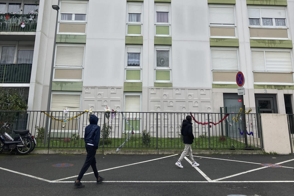 Men walk past a building after four children between nine months and 10 years old and their mother were found killed, Tuesday, Dec.26, 2023 in Meaux, east of Paris. A woman and her four children, between nine months and 10 years old, were killed in their apartment east of Paris in what the local prosecutor called an exceptionally violent crime. Authorities said the children's father was arrested Tuesday and is the primary suspect. (AP Photo/Nicolas Garriga)