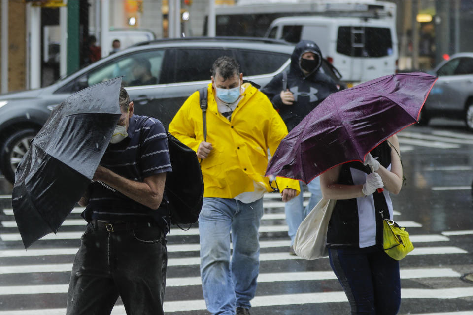 Pedestrians use umbrellas to protect themselves from inclement weather brought about by Tropical Storm Fay, Friday, July 10, 2020, in New York. Beaches closed in Delaware and rain lashed the New Jersey shore as fast-moving Tropical Storm Fay churned north on a path expected to soak the New York City region. (AP Photo/Frank Franklin II)