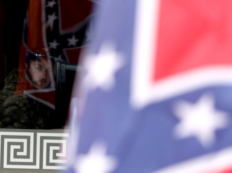 A man watches from a diner as supporters of the continued display of Confederate generals’ statues and other symbols march with Confederate flags in Lexington, Virginia