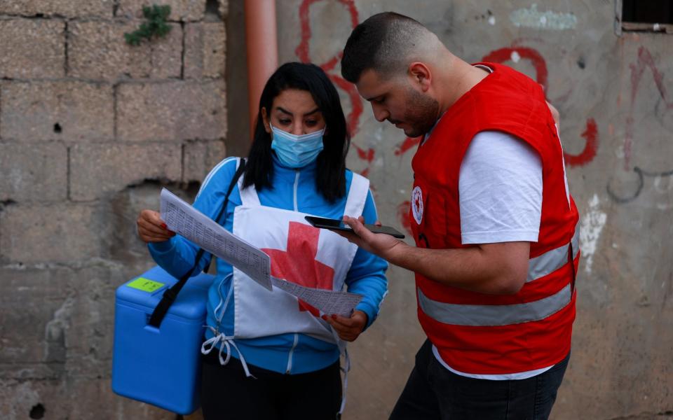 Se ve al personal de la Cruz Roja Libanesa en las calles de Bebnine, revisando el mapa del área para organizar la distribución de vacunas - ELISA ODDONE
