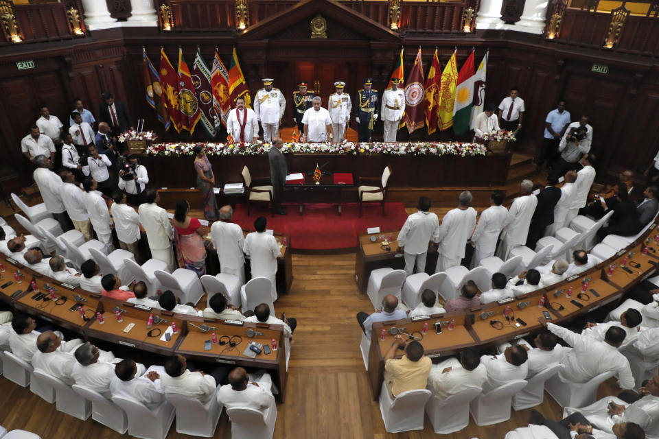 Sri Lankan President Gotabaya Rajapaksa, center, stands during an oath-taking ceremony of his new cabinet members in Colombo, Sri Lanka, Friday, Nov. 22, 2019. Rajapaksa, who was elected last week, said he would call a parliamentary election as early as allowed. The parliamentary term ends next August, and the constitution allows the president to dissolve Parliament in March and go for an election. (AP Photo/Eranga Jayawardena)