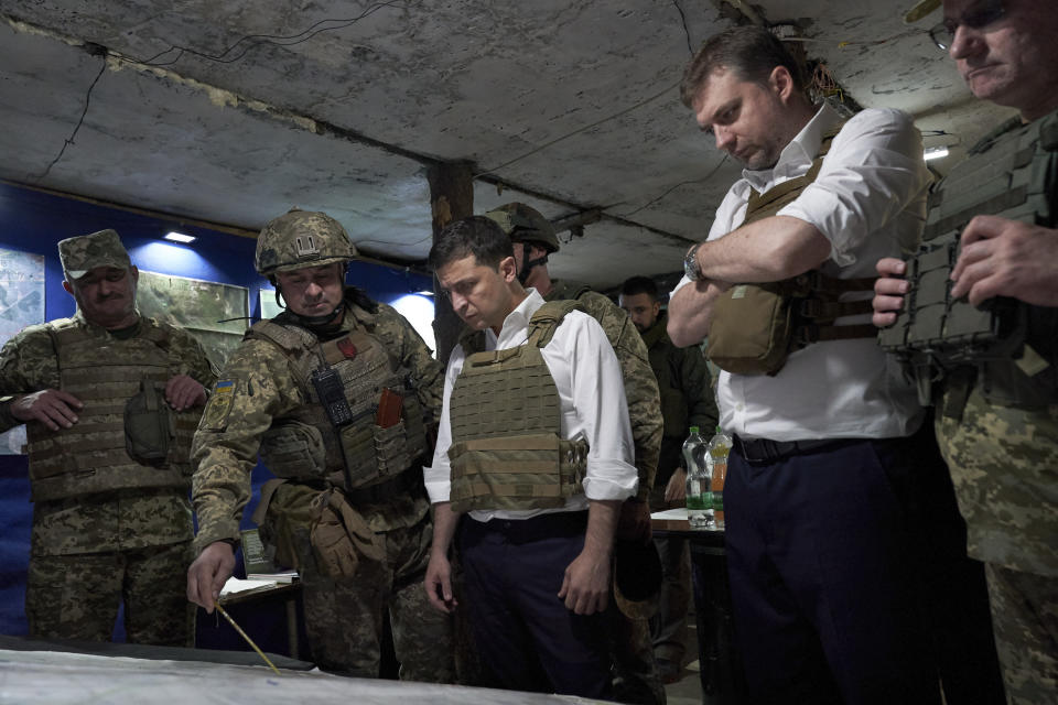 Ukrainian President Volodymyr Zelenskiy, center, listens to a serviceman as he visits the war-hit Donetsk region, eastern Ukraine, Monday, Oct. 14, 2019. (Ukrainian Presidential Press Office via AP)