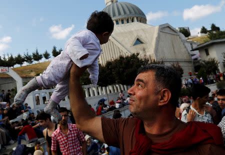 Syrian Kurd Salah ad-Din lifts his 7-month-old daughter Hiro Belo as they wait at the main bus station in Istanbul, Turkey, September 15, 2015. REUTERS/Murad Sezer