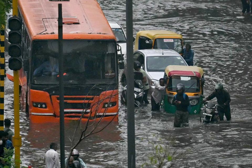 Commuters wade through flooded streets (AFP via Getty Images)