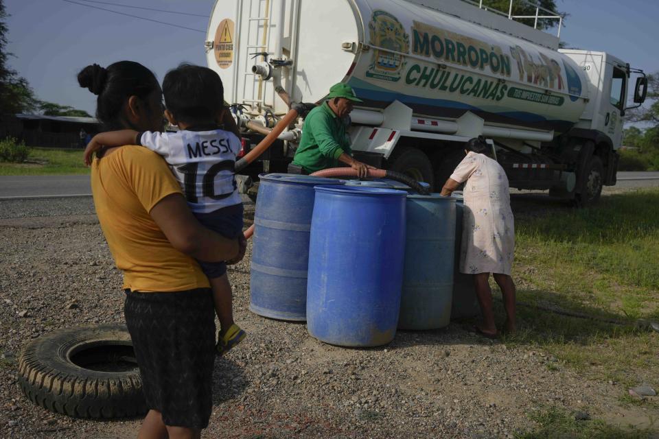 A water distribution worker fills an empty barrel for resident Santos Suyon in Santa Rosa, Chulucanas, Peru, one of many areas where a health emergency was declared due to rising dengue cases, Wednesday, Feb. 28, 2024. Once a week, residents in this area fill barrels with water from a distribution truck and use it for all their water needs. (AP Photo/Martin Mejia)